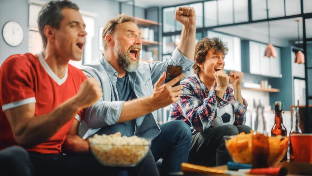 Adults watching a game with drinks on a table